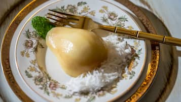 A plate with a dessert, possibly a pudding, on a floral-patterned plate with a gold rim.