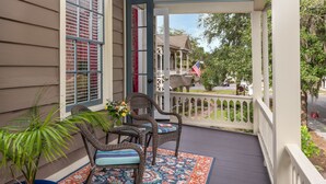 Eine Veranda mit Korbstühlen, einem Blumentopf und einem Zierteppich.