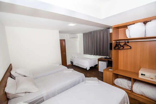 Habitación de hotel con dos camas individuales, un armario de madera, un escritorio y una mesita de noche pequeña.