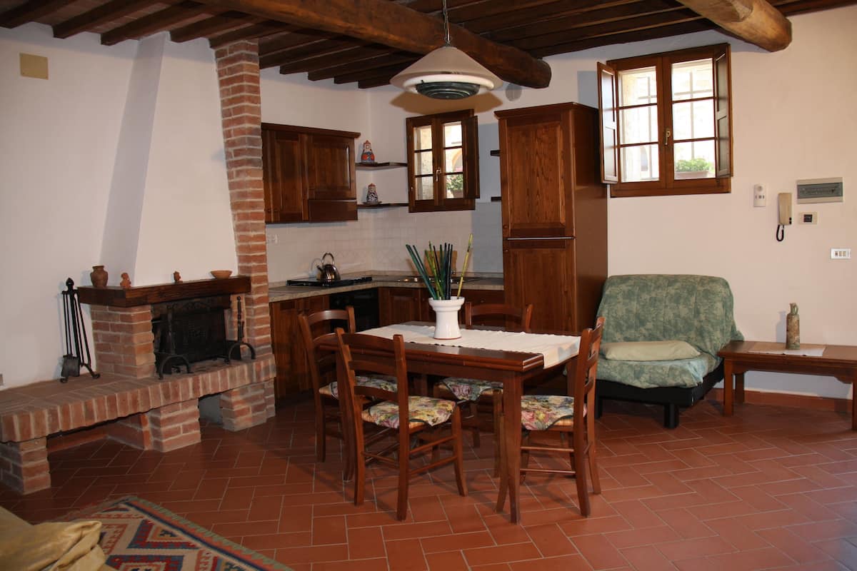 A traditional kitchen with a brick fireplace, wooden cabinets, and a dining table with chairs.