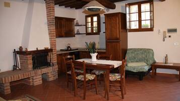 A traditional kitchen with a brick fireplace, wooden cabinets, and a dining table with chairs.