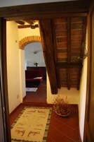Un pasillo con suelo de baldosas, un sofá rojo, techo de madera y un arco de ladrillo.