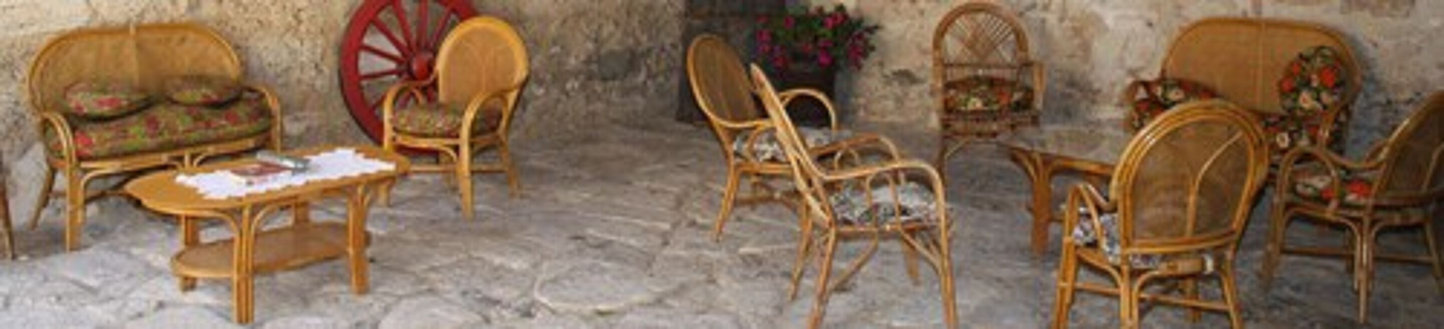 Une pièce rustique meublée de mobilier en osier, notamment des chaises et un canapé, et ornée d’une grande roue en bois.