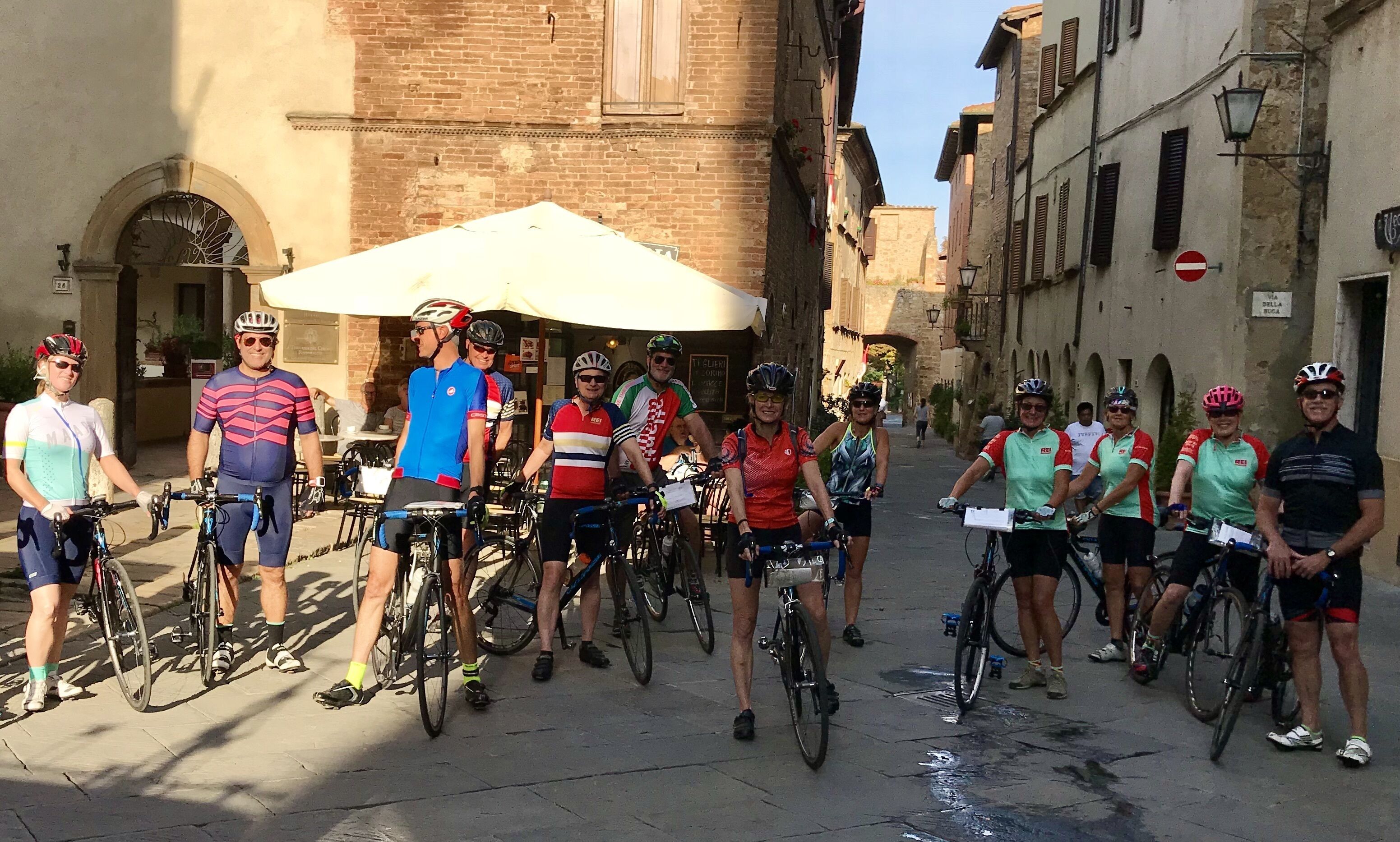 En gruppe cyklister på en smal gade med historiske bygninger.