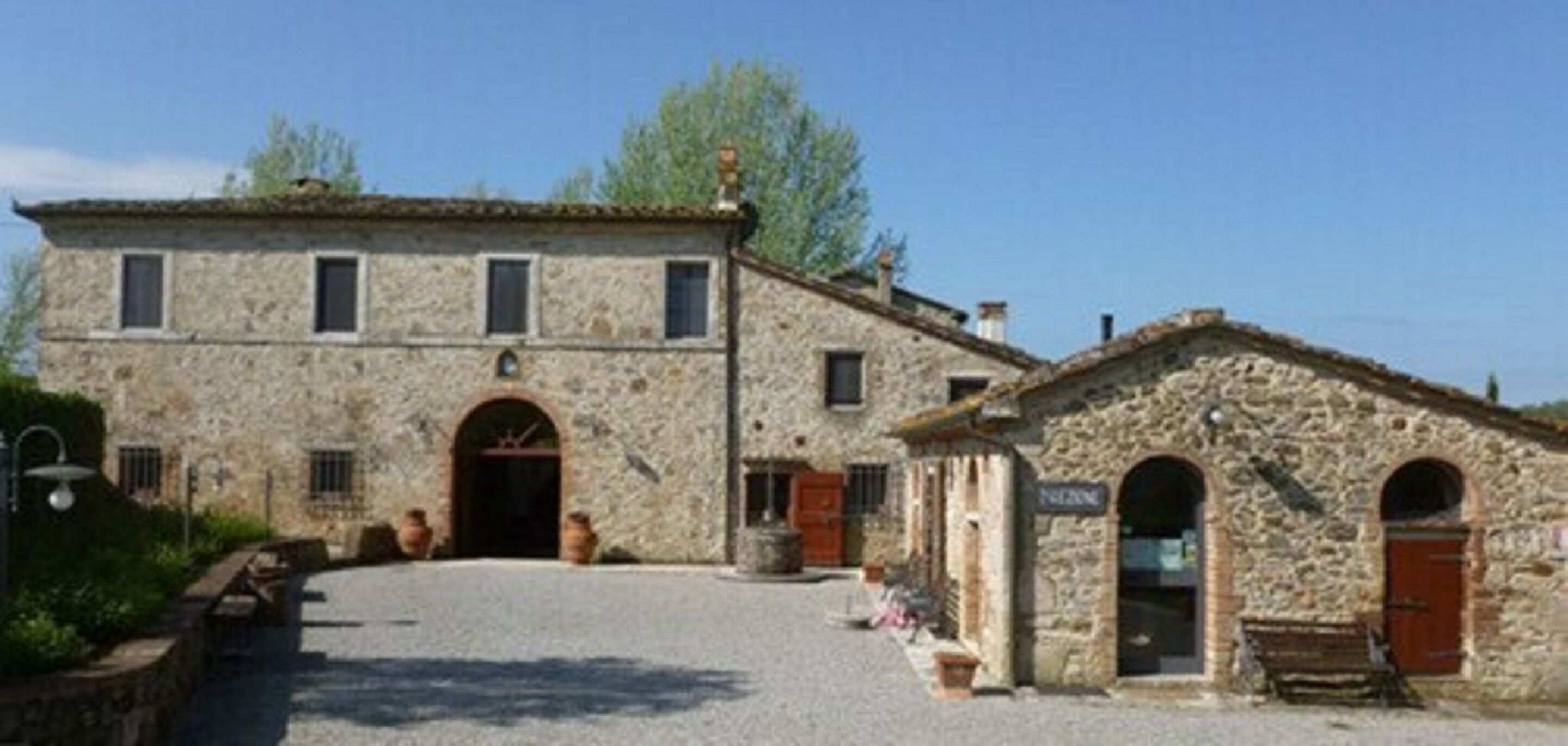 Un edificio de piedra con una entrada central en arco y una estructura adosada más pequeña con ventanas arqueadas.