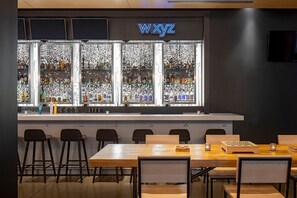 A bar area with a neon sign, shelves of bottles, and a chessboard on the table. - Aloft by Marriott New Orleans Downtown (New Orleans)