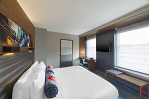 A modern hotel room with a large bed, a desk, a chair, a TV, and a window with a city view. - Aloft by Marriott New Orleans Downtown (New Orleans)