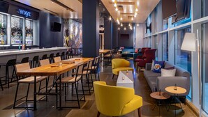 A modern bar area with a bar counter, seating arrangements, and a mural on the wall. - Aloft by Marriott New Orleans Downtown (New Orleans)