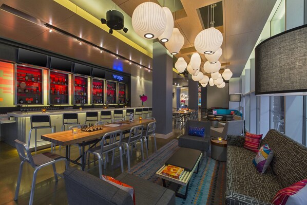 A modern hotel lobby with a bar area, seating arrangements, and decorative lighting. - Aloft by Marriott New Orleans Downtown (New Orleans)