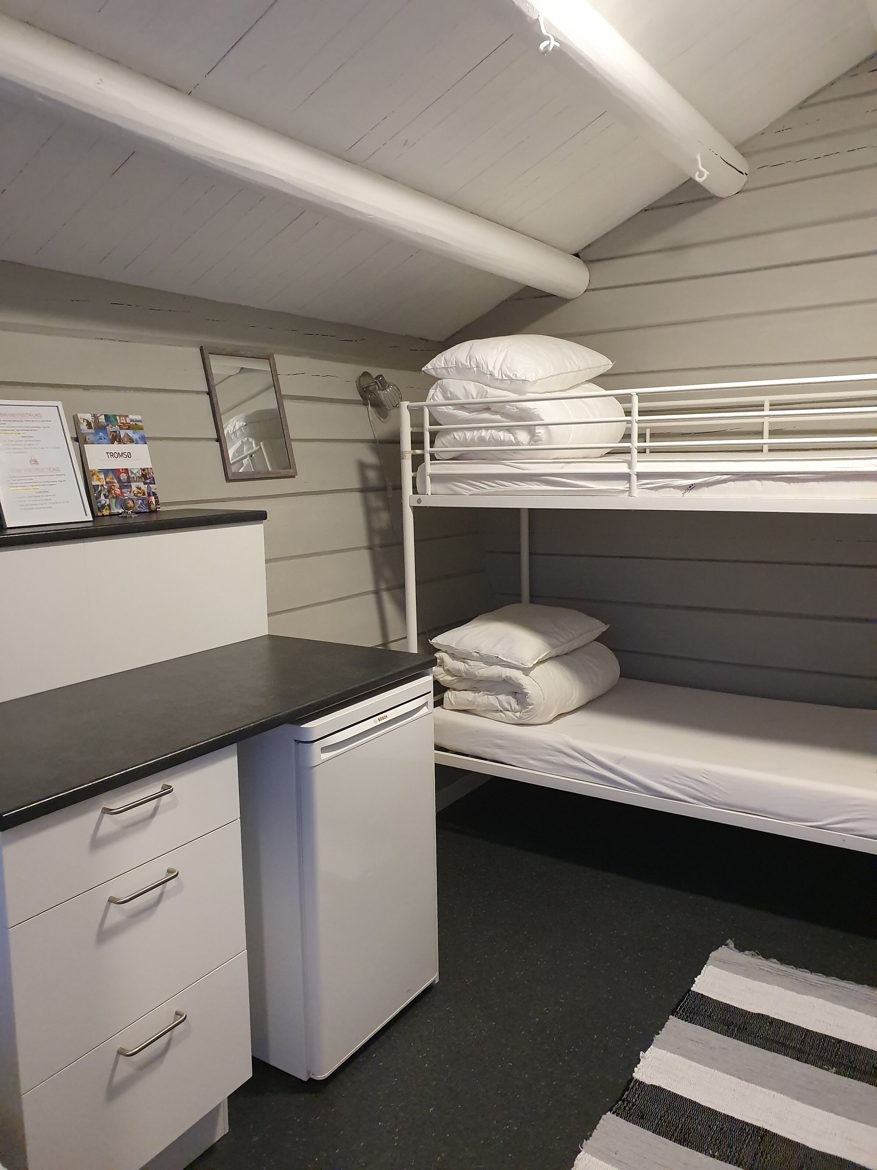 A bunk bed room with a desk and a small refrigerator.