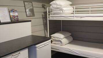 A bunk bed room with a desk and a small refrigerator.