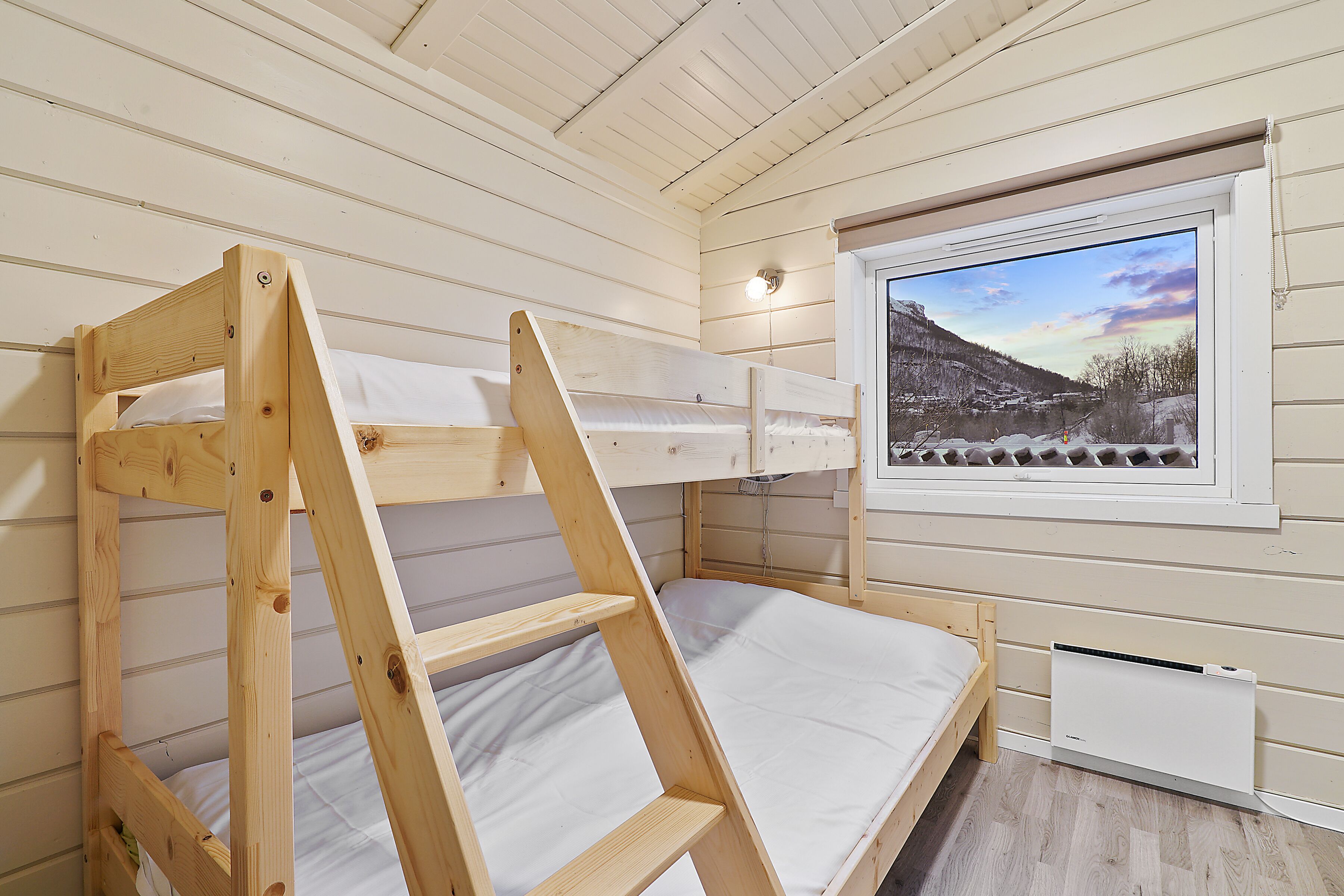 Un lit superposé avec vue sur un paysage enneigé par la fenêtre.