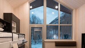 A modern cabin interior with a large window, wooden walls, and a bunk bed. - Tromsø Lodge & Camping (Tromsø)
