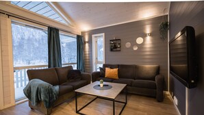 A modern living room with a sofa, a coffee table, and a TV. - Tromsø Lodge & Camping (Tromsø)