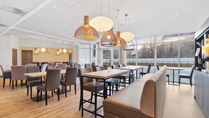 A modern dining area with wooden tables, cushioned benches, and pendant lighting. - Tromsø Lodge & Camping (Tromsø)