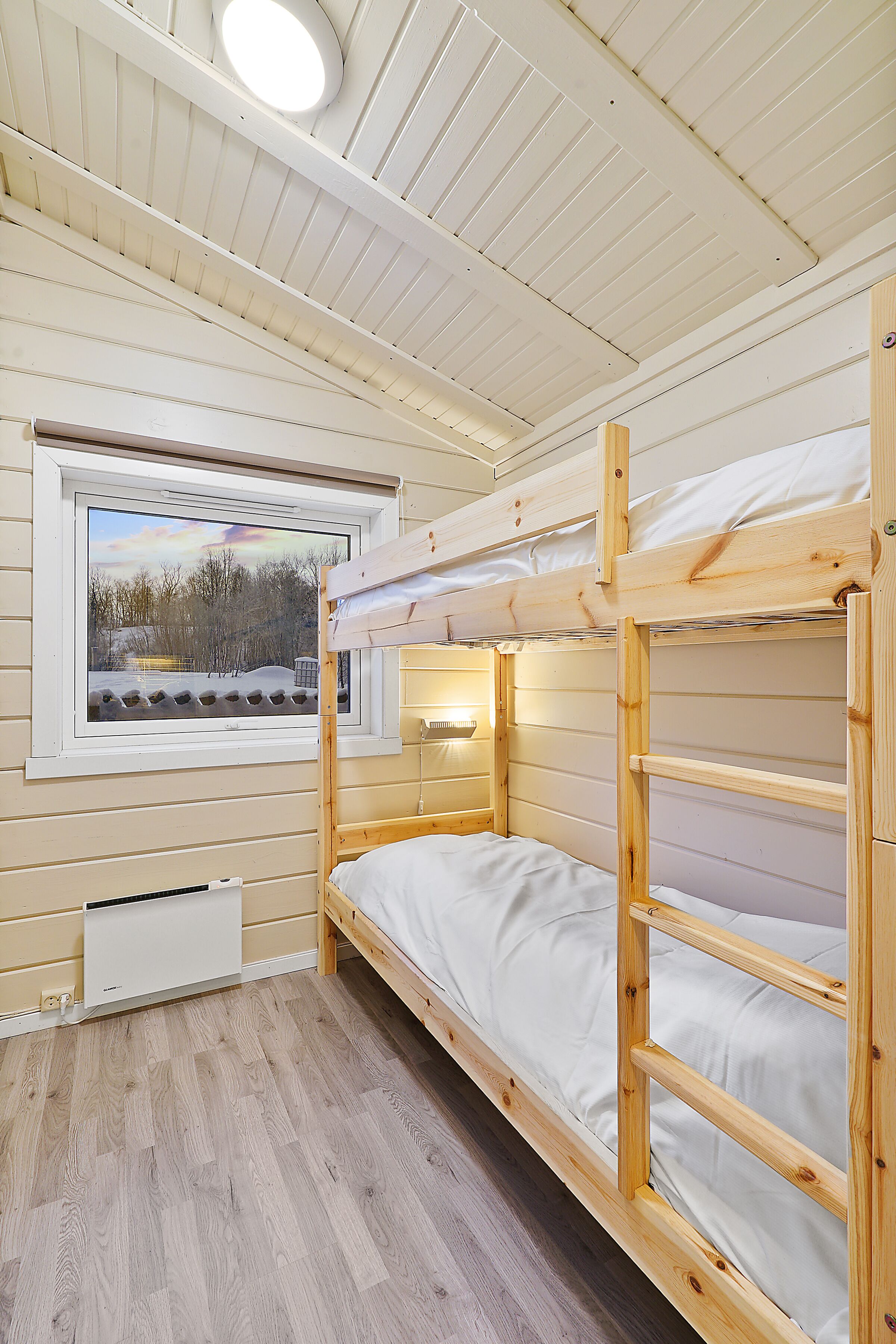 Dormitorio con literas, ventana, paredes de madera y luz en el techo.