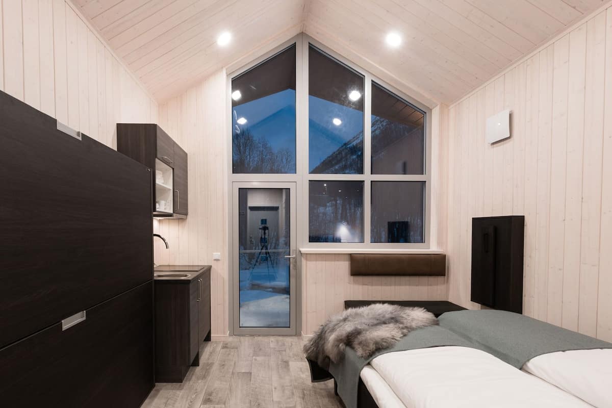 Ein Schlafzimmer mit großem Fenster, einem Bett, einem Schreibtisch und einem Kleiderschrank.