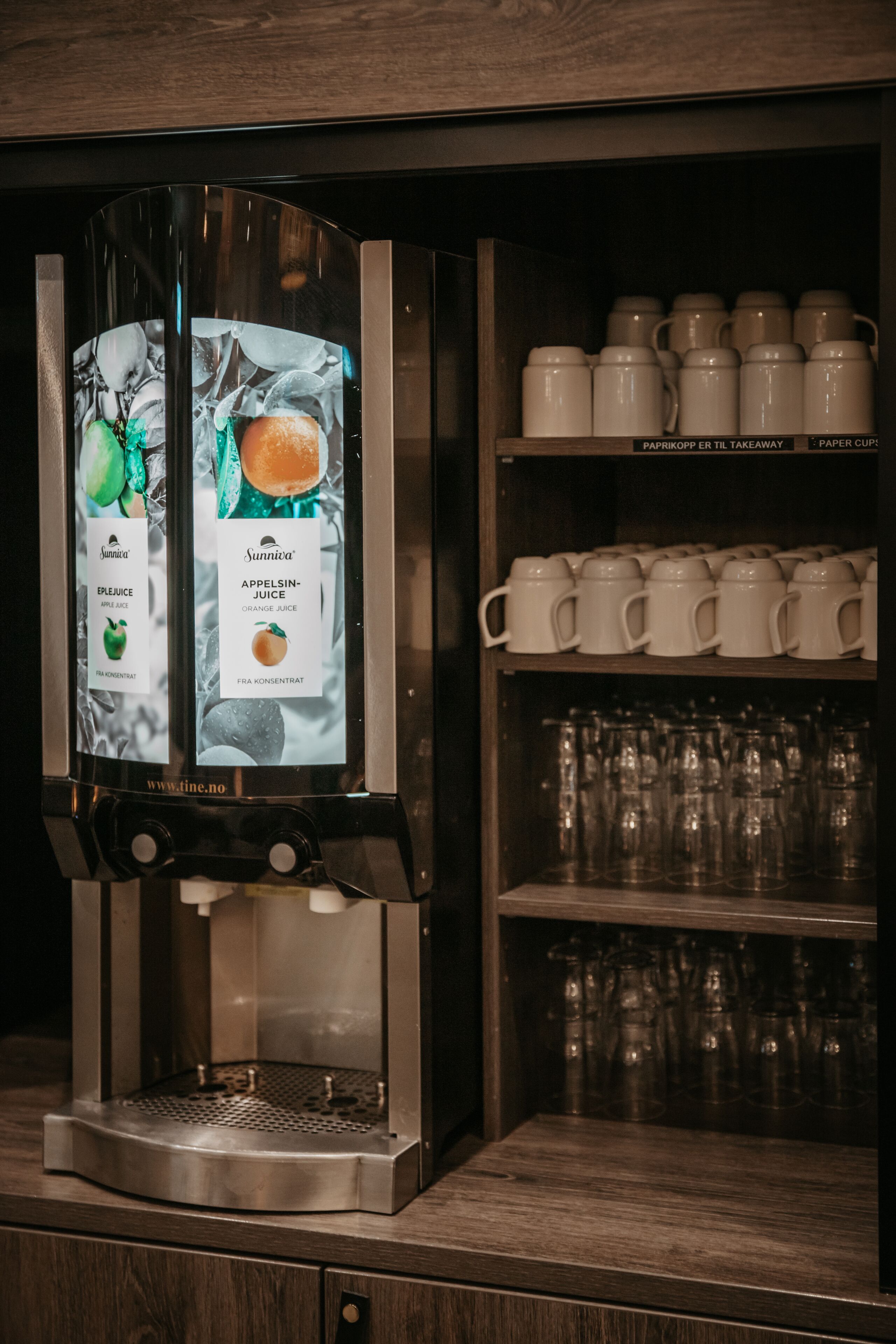 Une machine à café dotée d’un écran numérique et d’un assortiment de gobelets en papier.