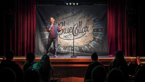 A stage with a backdrop labeled "BlueCollar Hotel" and a person speaking into a microphone. - Stayokay Eindhoven - Hostel (Eindhoven)
