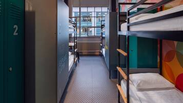 A bunk bed room with a metal ladder, a bunk bed on the right, a bunk bed on the left, and a metal locker on the left.