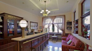 A reception area with a reception desk, a sofa, and a chandelier.