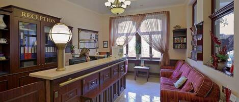 A reception area with a reception desk, a sofa, and a chandelier.