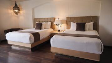 Two double beds with headboards, a bedside table with a lamp, and a hanging light fixture.