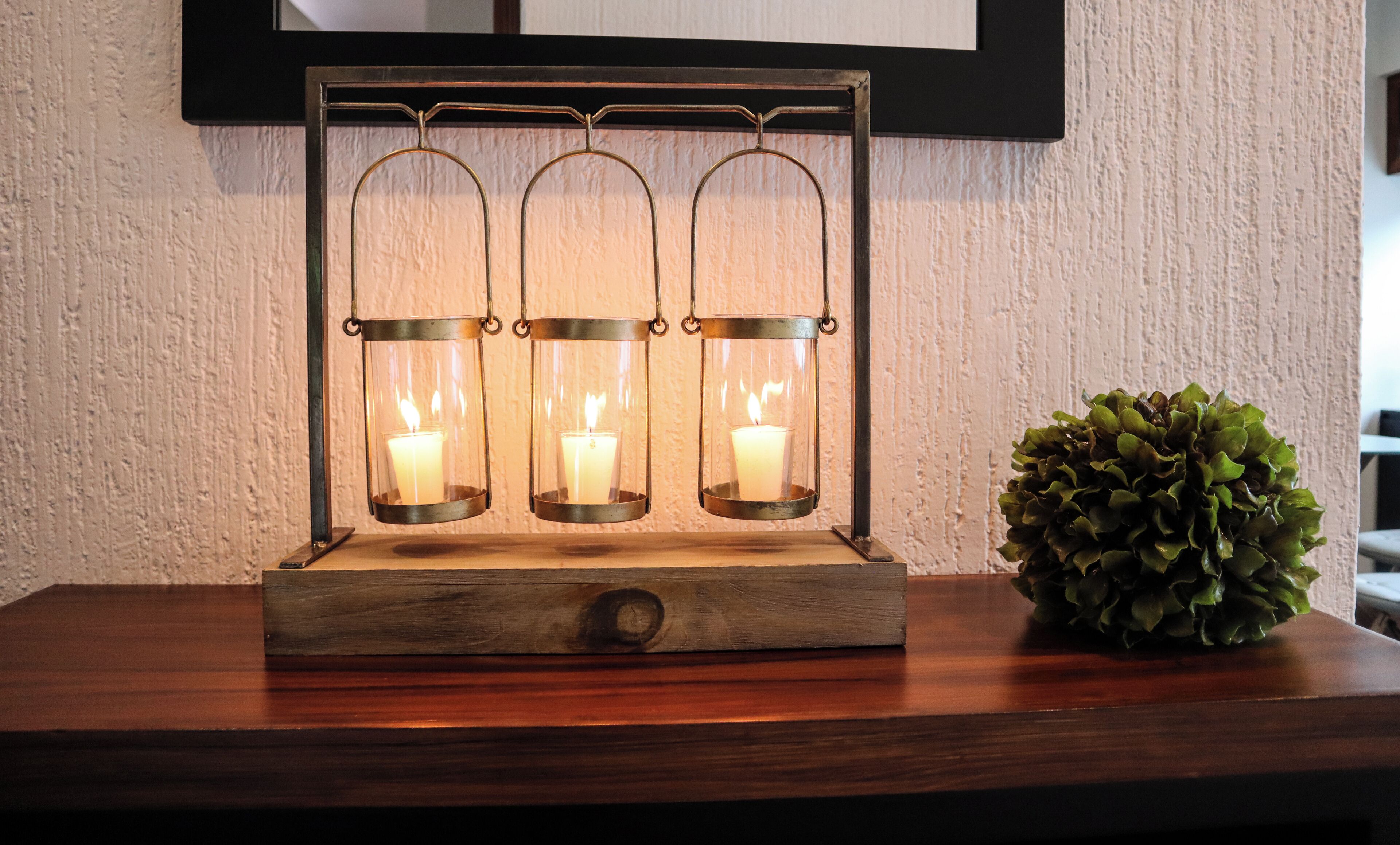 A wooden table with three lit candles in glass holders.