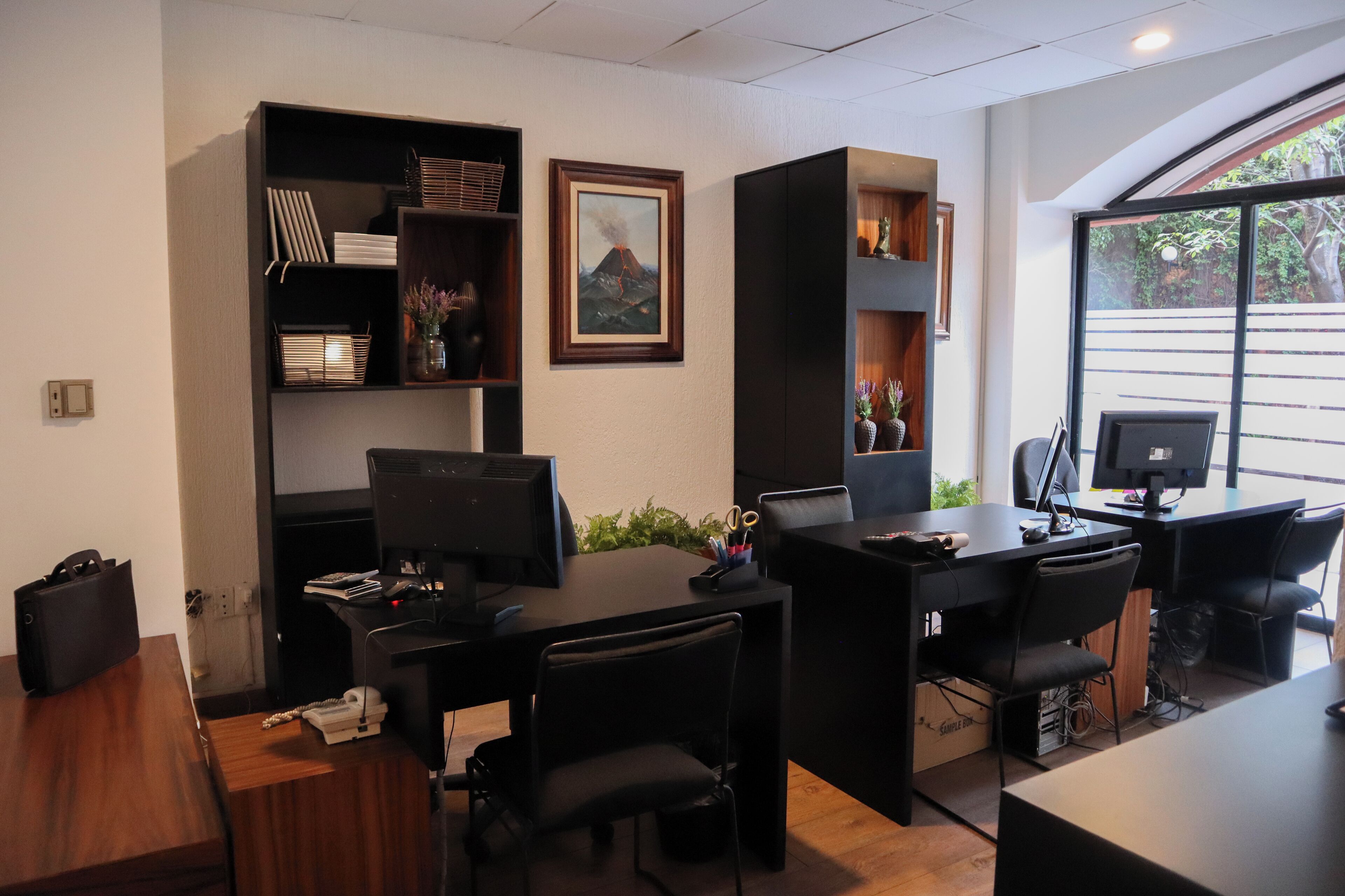 A modern office with desks, chairs, and shelves containing books and decorative items.