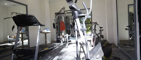 Un gimnasio con diversos equipos de ejercicio, como cintas de correr, elípticas y bicicletas estáticas.