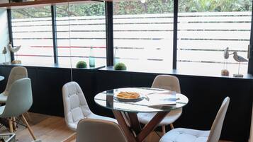 Un comedor moderno con una mesa redonda, sillas blancas tapizadas y vistas a la calle a través de amplias ventanas.