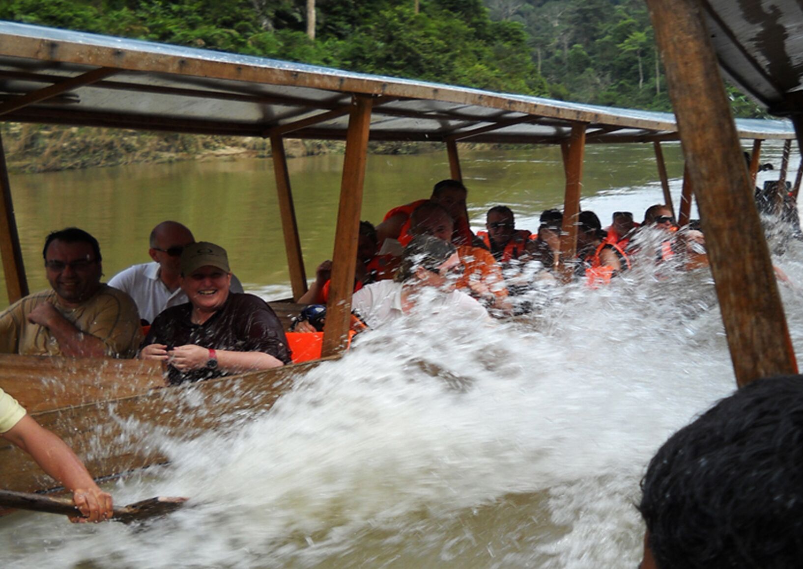 Un grupo de personas en un bote con techo, remando por un río.