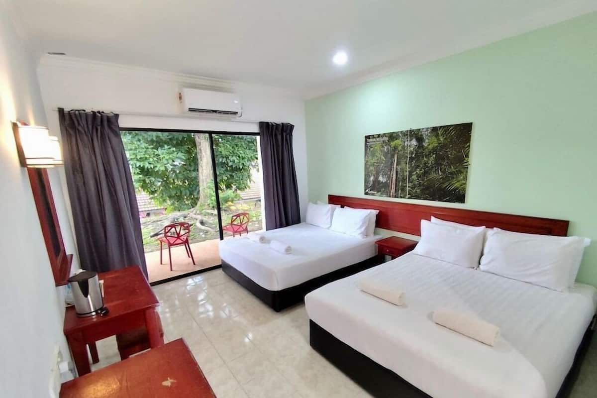 Habitación de hotel con dos camas, un escritorio, una silla y vistas al exterior.