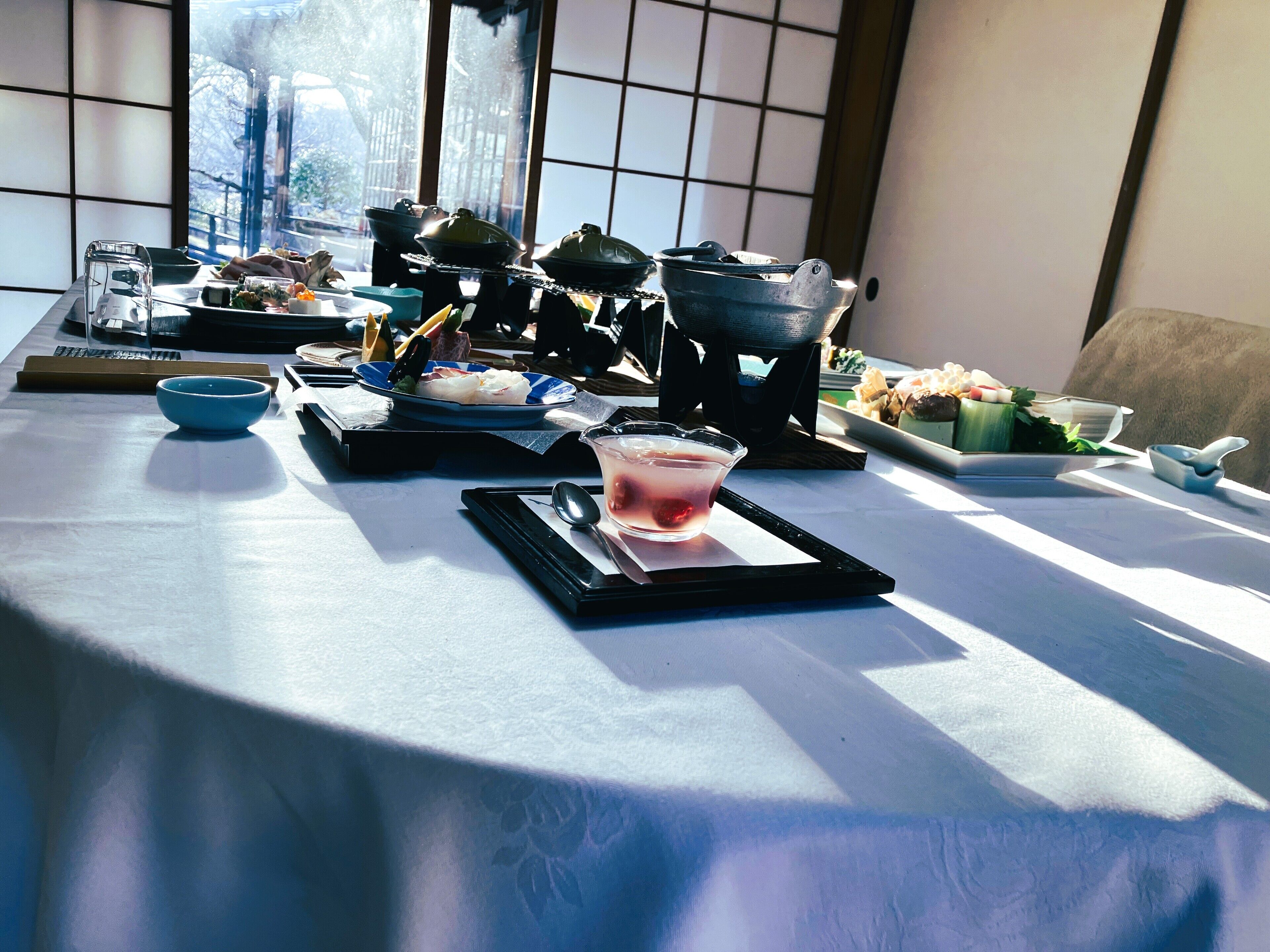 A dining table with various dishes and a drink, set in a room with large windows and traditional decor.