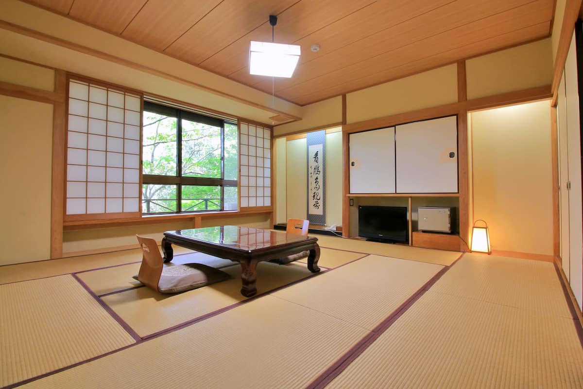 A tatami mat room with a low table, sliding doors, and a television.