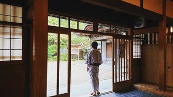 A person standing at a wooden door with glass panels, looking outside.