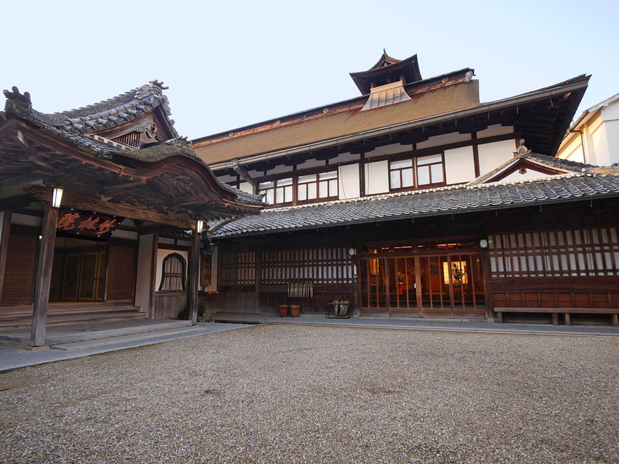 A traditional Japanese building with a tiled roof, wooden beams, and a gravel courtyard.