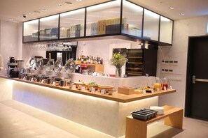 A modern bar area with a variety of beverages, a coffee machine, and a selection of glasses.