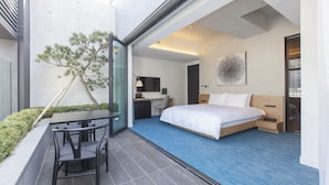 A modern hotel room with a bed, desk, chair, and a small balcony with a tree. - STAY B Hotel Myeongdong (Seoul)