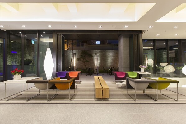 A modern lobby with a central seating area, glass walls, and a brick wall in the background.