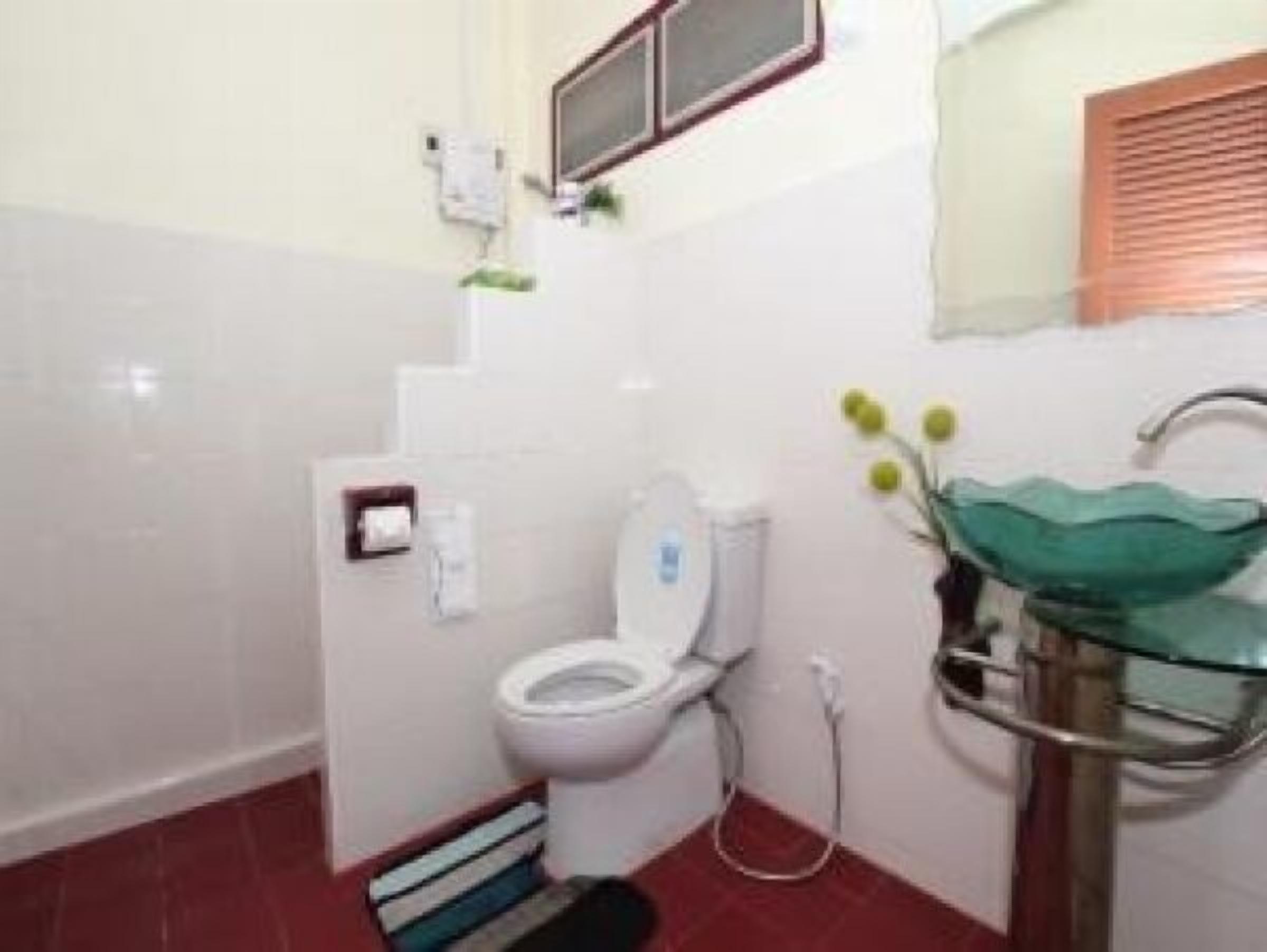 Un baño con inodoro, lavamanos de vidrio y zona de ducha.