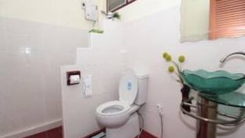 Un baño con inodoro, lavamanos de vidrio y zona de ducha.