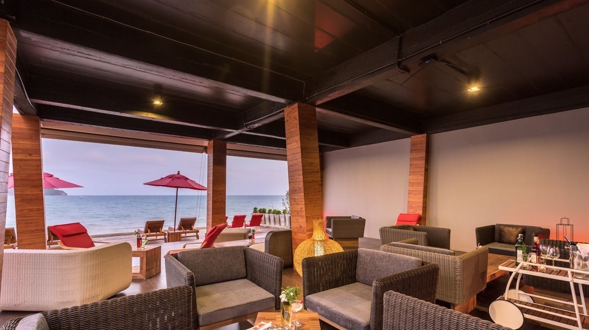 A lounge area with wicker furniture, a large vase, and a view of the sea.