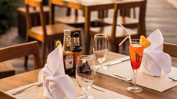 Una mesa de comedor de madera dispuesta con una botella de Heineken, un vaso con un cóctel y una servilleta.