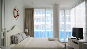 Habitación de hotel con una cama grande, televisión, escritorio y vista al balcón.