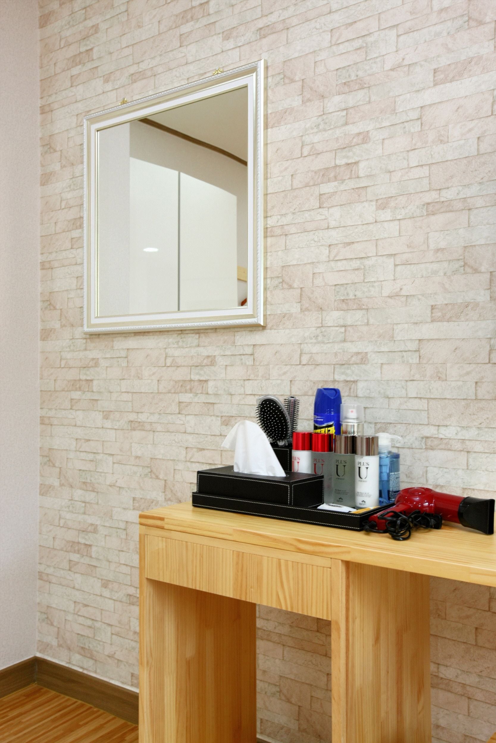 Una habitación con pared de ladrillo, un espejo y una mesa de madera con artículos de aseo.