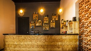 Una zona de bar con mostrador de madera, estantes con botellas y lámparas colgantes.