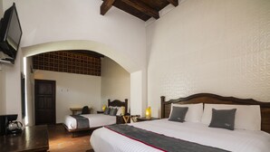 Habitación de hotel con dos camas, un escritorio, una cafetera y un televisor.