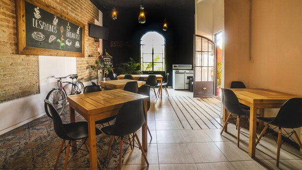 Un café con mesas y sillas de madera, un menú en una pizarra y una bicicleta.