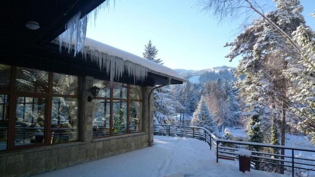 A snow-covered building with large windows and icicles hanging from the roof. - Hotel Bor (Samokov)
